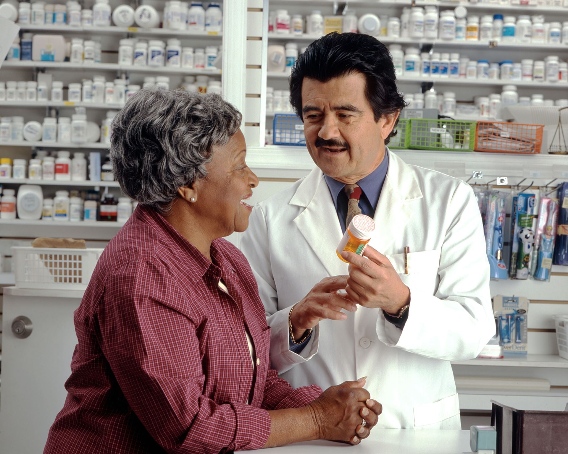 A pharmacist hands a bottle of pills to a woman