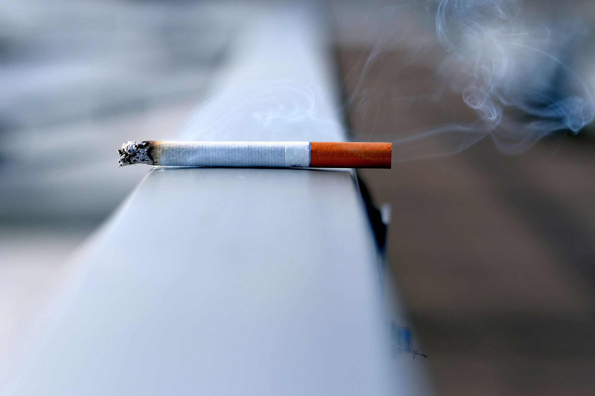 A burning cigarette sitting on a railing