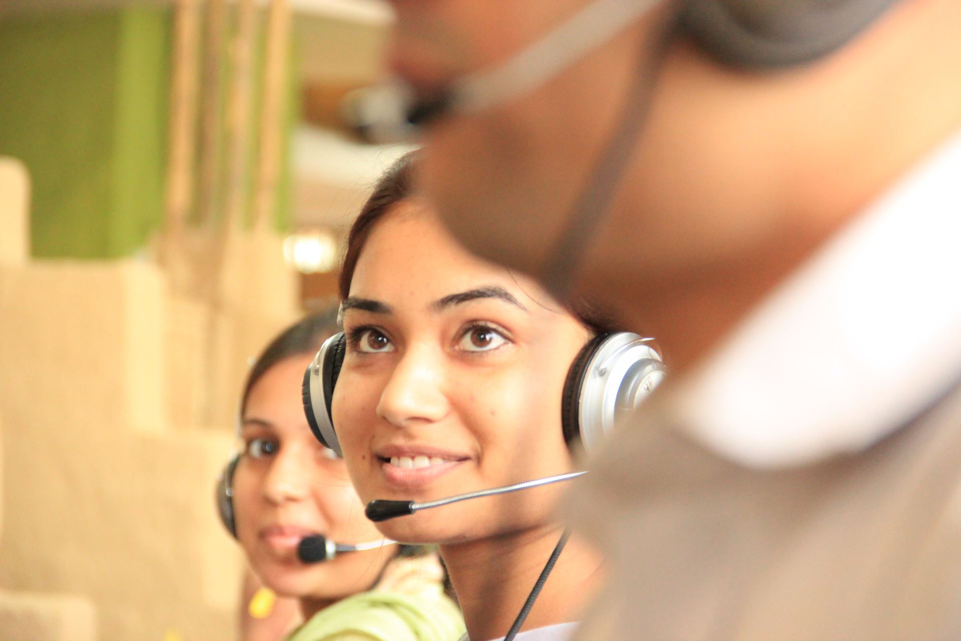 A smiling lady wearing a headset working in a call centre